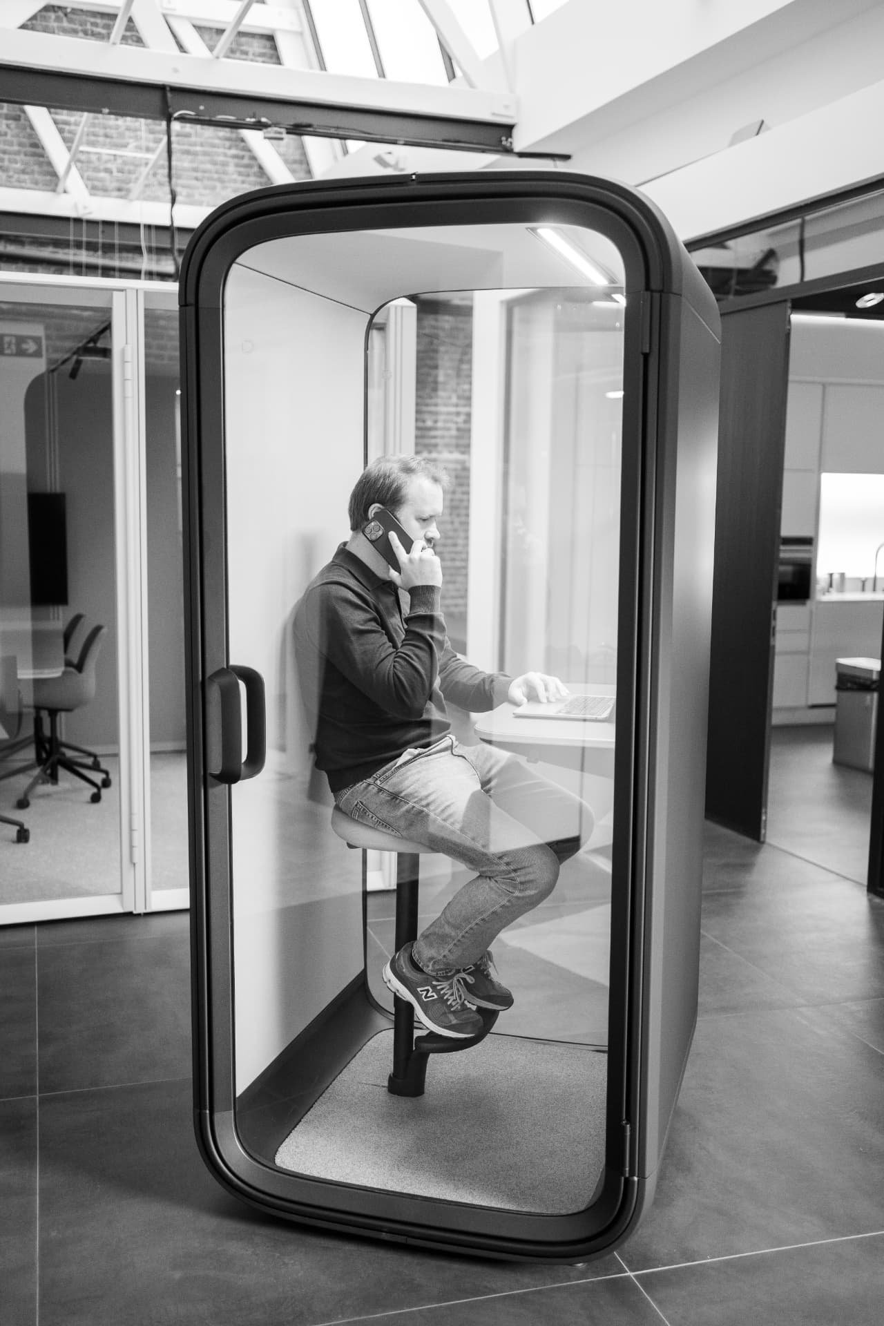 Ondernemer belt vanuit een telefooncel met zijn laptop open